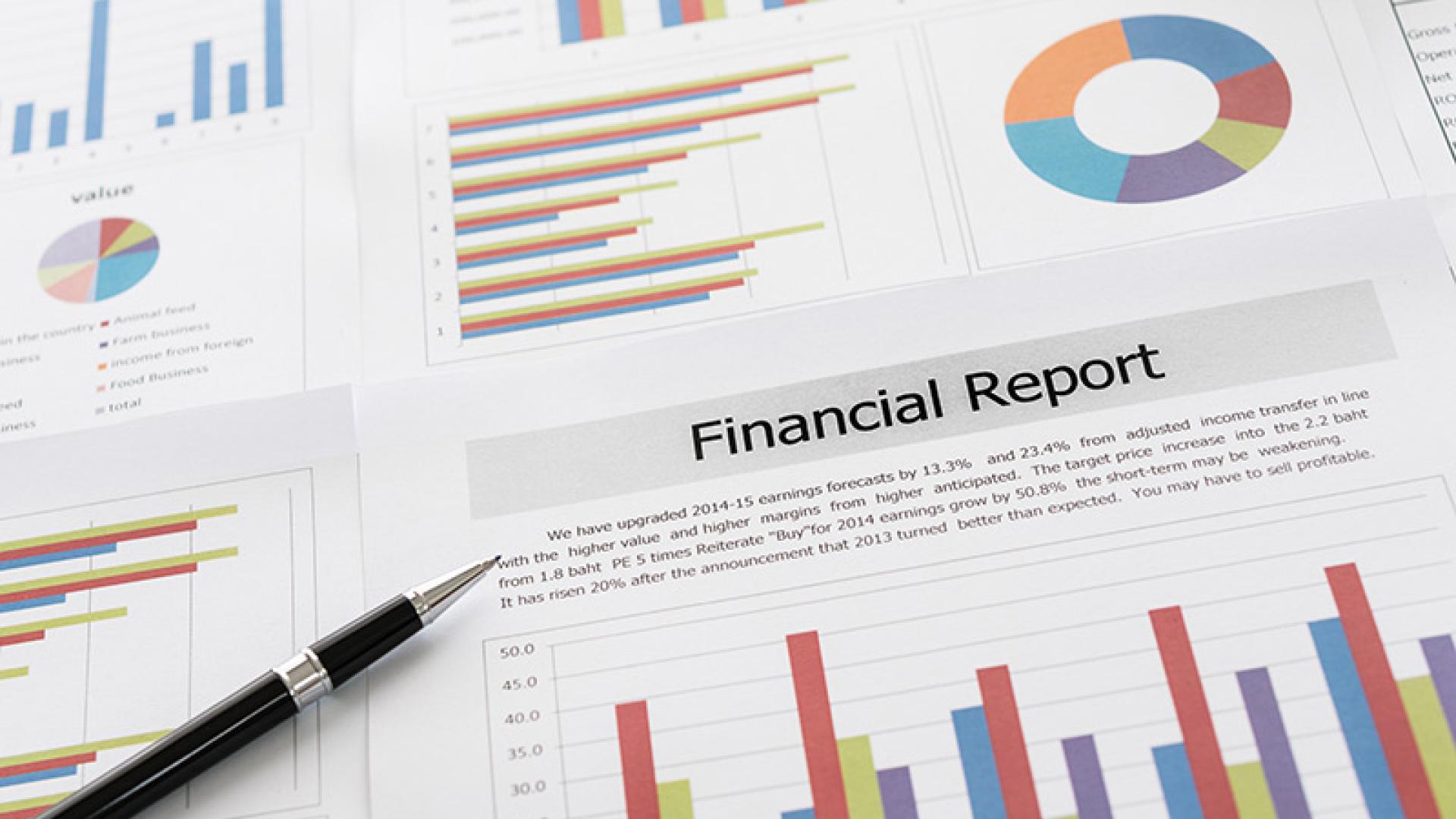 A pen on top of a color print of a financial report with charts and graphs.