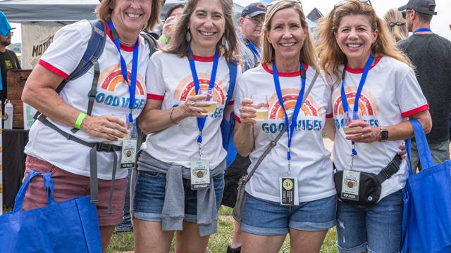 Four happy women wearing matching shirts that say Good Vibes participating in beer festival tastings.