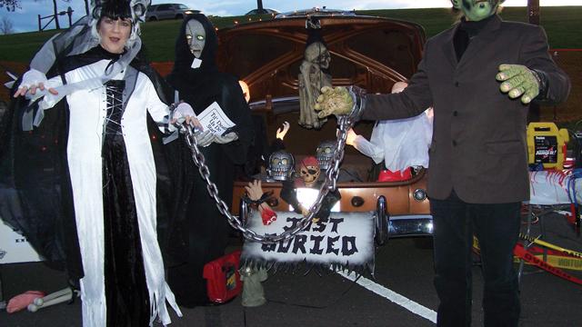 Frankenstein and Bride standing by a decorated trunk.
