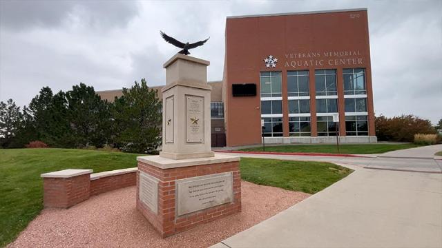 Large pillar with golden stars and engraved text. Bronze eagle statue on top on top of the pillar in front of the Veterans Memorial Aquatic Center.