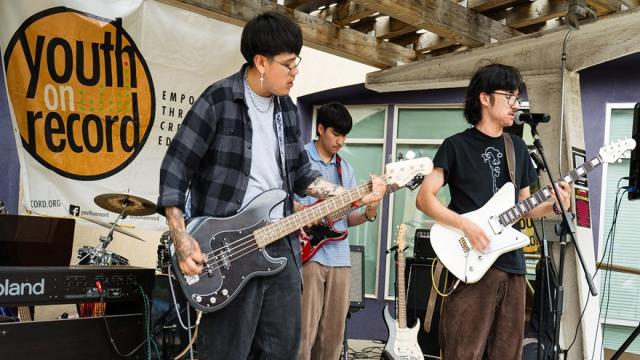 Three teens playing electric guitars on stage