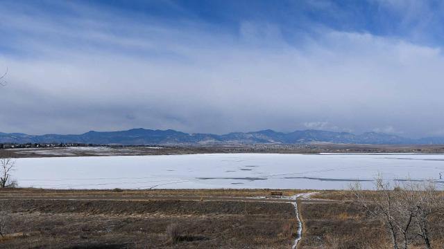 Standley Lake frozen with Colorado mountains in the background.