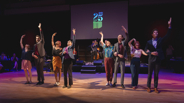 Eight adult dancers on stage waving to audience