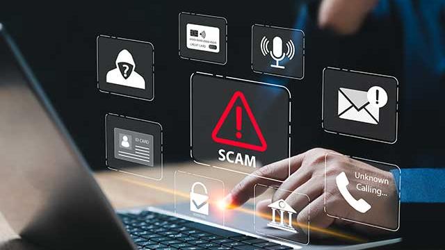 Scam alert hovering over a laptop with someone tapping a key.