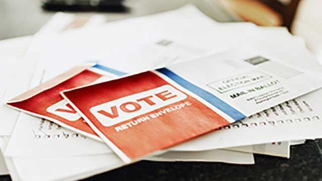 Voting envelope on a pile of papers on a counter.