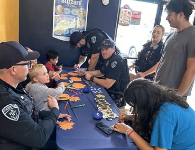 Police officers and children at a table doing arts and crafts