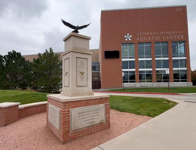 Large pillar with golden stars and engraved text. Bronze eagle statue on top on top of the pillar in front of the Veterans Memorial Aquatic Center.