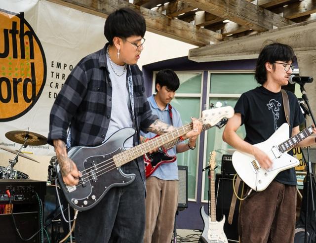 Three teens playing electric guitars on stage