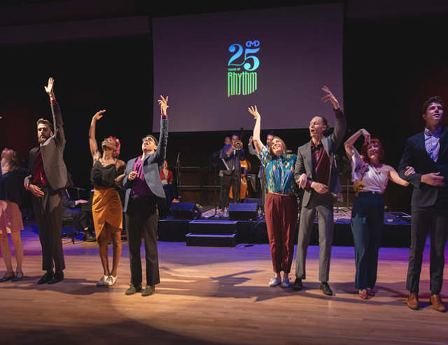 Eight adult dancers on stage waving to audience