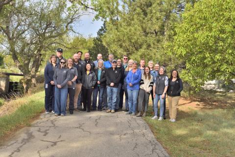 A group of people standing on an asphalt through a grassy pathway