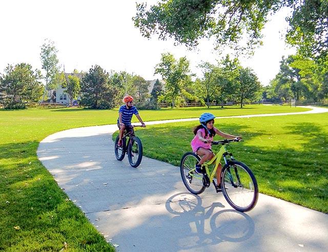 Two kids riding their bikes along a park trail.